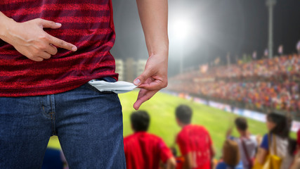 Man showing his empty pockets on blurred soccer stadium.