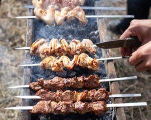 A man fries kebabs on skewers on the grill