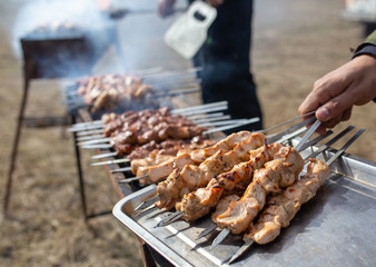 A man fries kebabs on skewers on the grill