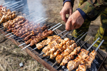 A man fries kebabs on skewers on the grill