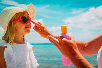 sun protection - mom put suncream on little girl face at beach - 253243801