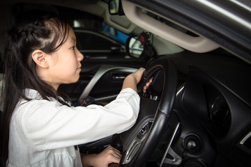 Obraz na płótnie Canvas Asian little girl driving a car