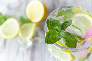 Lemonade with ice and fresh lemon with mint on wooden background. horizontal view. copy space. close-up. refreshing summer drink.