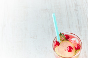 Refreshing summer drink with berry and lemon on a light wooden table. The concept of summer drinks with ice. glass with summer cocktail with straw.