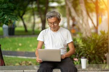 The elderly man used laptop in park