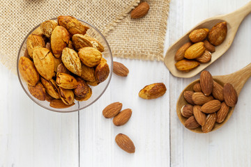Almonds in a black bowl against dark rustic wooden background