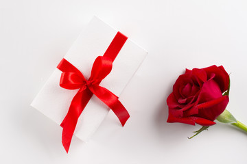 Beautiful bud velvet red rose flower and white gift box with red ribbon on white background