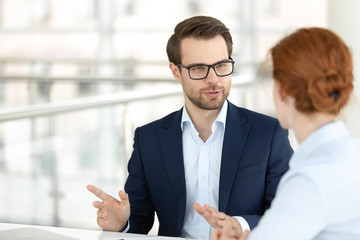 Handsome smiling male office worker talking with female colleague