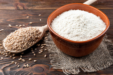 Fototapeta na wymiar Wheat flour on dark wooden background.