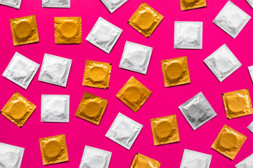 Condoms in pink background, top view. Large amount of condoms, shot from above - safe sex and contraception concept