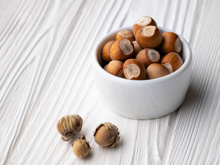 Group of hazelnuts in a white cup on a wooden table made of aged wood