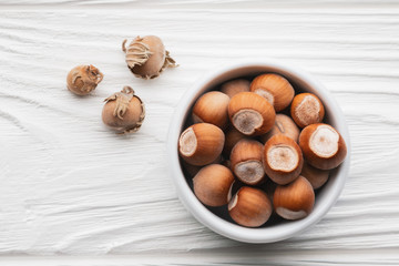 Top view hazelnuts in a white bowl on a white wooden table