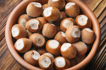 Shot from above lots of hazelnuts in a clay bowl on a wooden table