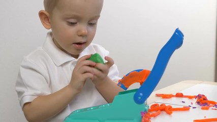 A two years old preschool child playing with modeling clay (compound). Smiling and looking at the camera. Early childhood education to children concept