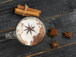 Fototapeta na wymiar Homemade tea latte with cinnamon and anise on wooden rustic black background in glass mug