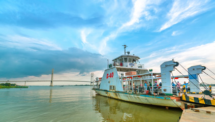 Fototapeta na wymiar Dong Thap, Vietnam - January 16th, 2019: Landscape ferry about to leave port to transport passengers across Mekong river in spring, far away is Cao Lanh bridge just completed in Dong Thap, Vietnam.