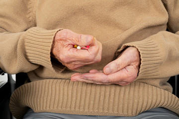 Elderly hands holding pills