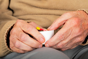 Elderly hands holding pills