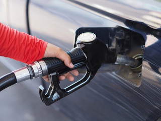 Closeup hand man pumping gasoline fuel in car at gas station.