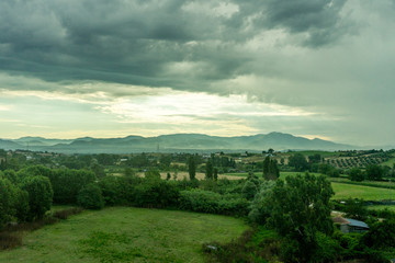 Italy, Rome to Florence train, a large green field with clouds in the sky