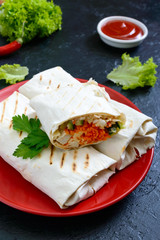Delicious shawarma sandwich on a black background. Burritos wraps with grilled chicken and vegetables, greens. Fajitas, pita bread. Traditional Middle Eastern appetizer. Mexican cuisine