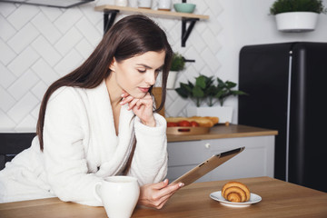 Longhaired woman using digital tablet in kitchen at home