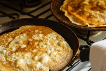 Thin pancakes in a pan on the stove