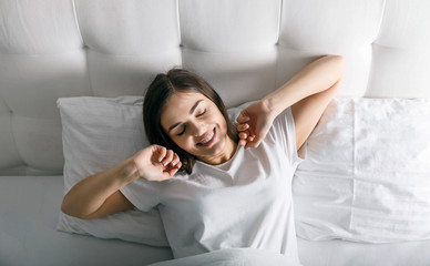 Cute woman waking up at her white bed
