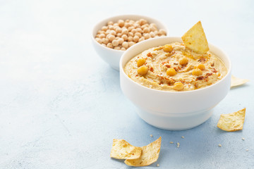 Hummus dip served with chickpeas, chips and paprika.