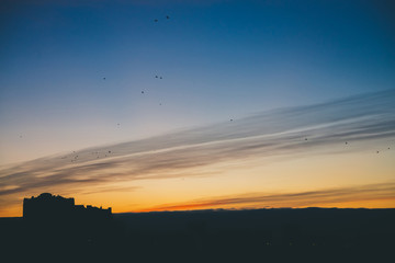 Cityscape with wonderful varicolored vivid dawn. Amazing dramatic blue cloud sky above dark...