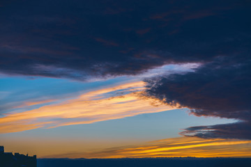 Cityscape with wonderful varicolored vivid dawn. Amazing dramatic blue cloud sky above dark...