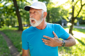 Senior man with chest pain suffering from heart attack during jogging