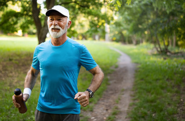 Attractive retired man with a nice smile jogging in park