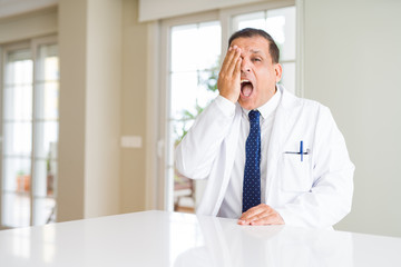 Fototapeta premium Middle age doctor man wearing medical coat at the clinic covering one eye with hand with confident smile on face and surprise emotion.