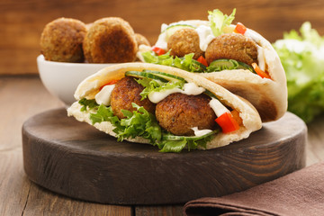 Falafel and fresh vegetables in pita bread with sauce.