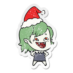 distressed sticker cartoon of a laughing vampire girl wearing santa hat