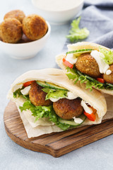 Pita breads with falafel, fresh vegetables and sauce.