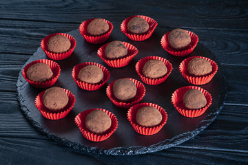 Close up view on Delicious truffle candies with rum on a black background and a plate. Flat lay sweets. Picture for menu, background or design with copy space.