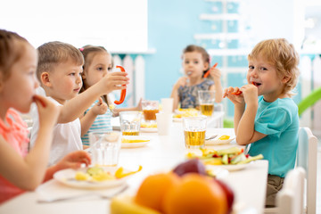 Group of kindergarten students eating healthy food lunch break together