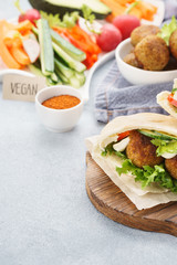 Pita breads with falafel, fresh vegetable sticks and sauce.