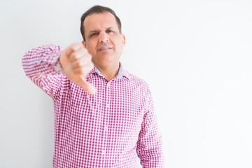 Middle age man wearing business shirt over white wall looking unhappy and angry showing rejection and negative with thumbs down gesture. Bad expression.