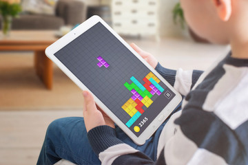 Kid play tetris game on his tablet. Entertainment for children concept.