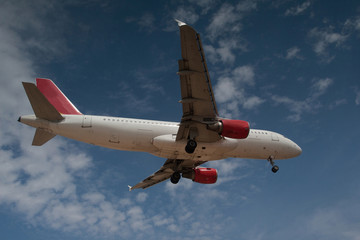 Fototapeta premium Passenger plane in the blue sky with clouds landing at Mai Khao airport in Thailand