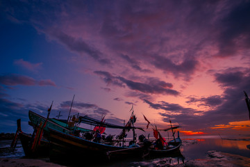 Fototapeta premium The background of the fishing boats is docked at the beach, with colorful skies in the morning, the natural beauty and the coexistence of fishermen on the waterfront