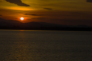 Close nature view Of the colorful sky (golden yellow) of the sun in the morning by the lake, behind the mountain, a beautiful journey