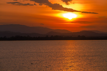 Close nature view Of the colorful sky (golden yellow) of the sun in the morning by the lake, behind the mountain, a beautiful journey