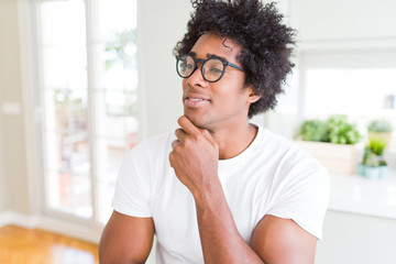 Fototapeta na wymiar African American man wearing glasses with hand on chin thinking about question, pensive expression. Smiling with thoughtful face. Doubt concept.