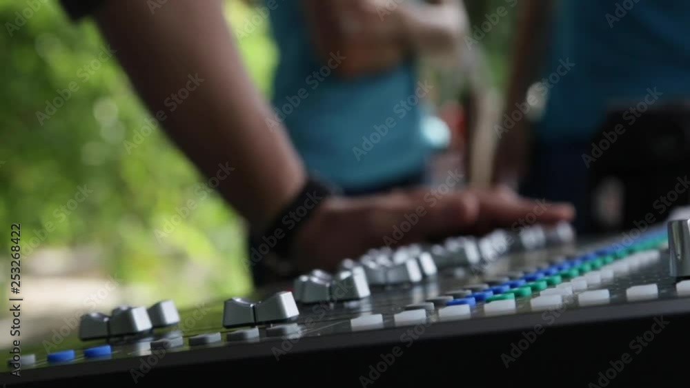 Poster pan across the soundboard at a show while the sound engineer presses a button.