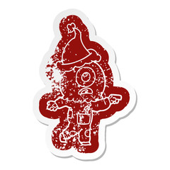 cartoon distressed sticker of a cyclops alien spaceman pointing wearing santa hat