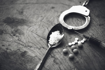 Drug syringe and cooked heroin on spoon and handcuffs . Concept - punishment for possession of...